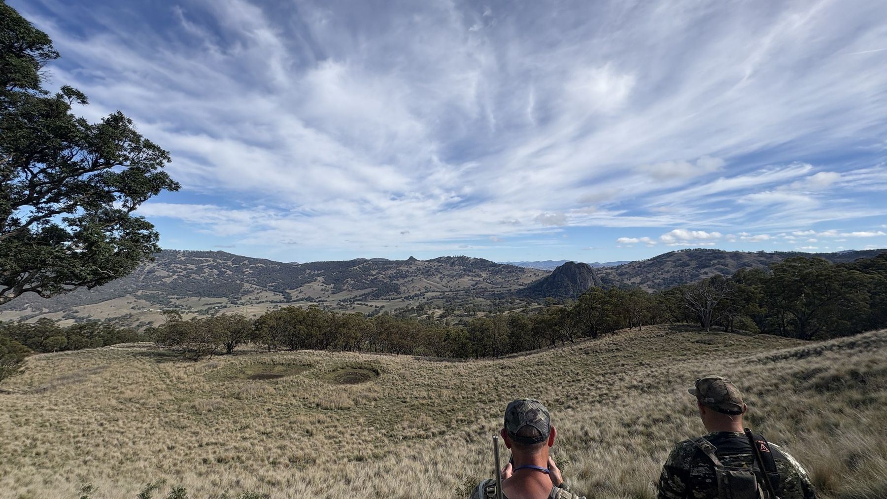 Two hunters in camo glassing across grassy hills and timbered ridges in the Upper Hunter